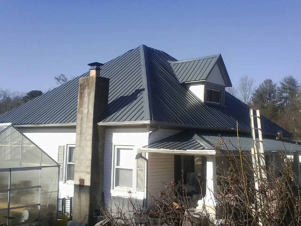 Dark blue standing seam metal roof on a white farmhouse with dormer — Slate & Tile Roof Repair by Roofing Brothers in Horse Shoe