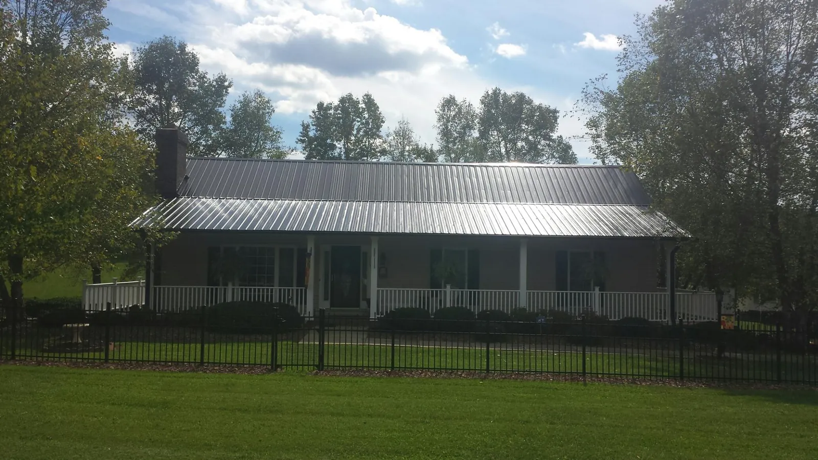 Gray metal roof on a brick ranch with a full width front porch — Gutter Guard Installation work by our crew in Horse Shoe