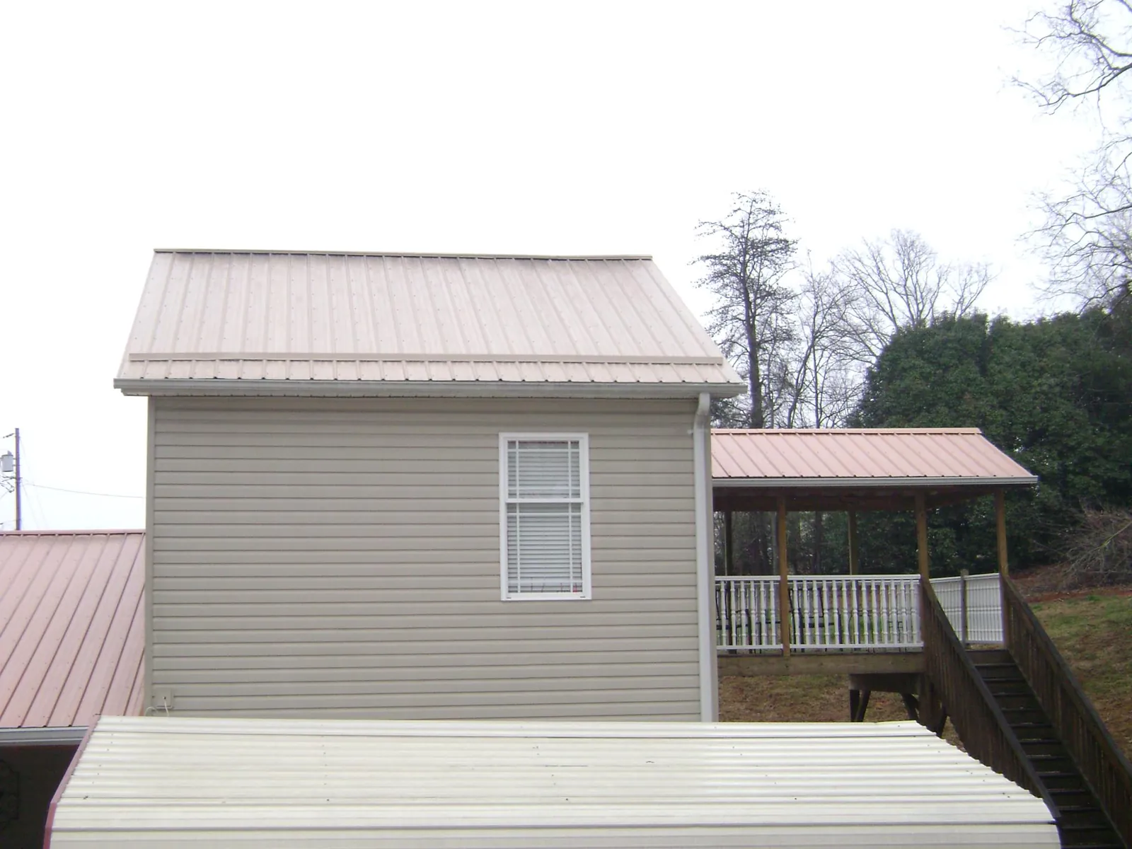 Tan metal roofs on a two story addition and attached porch, from a Roof Replacement job in Horse Shoe