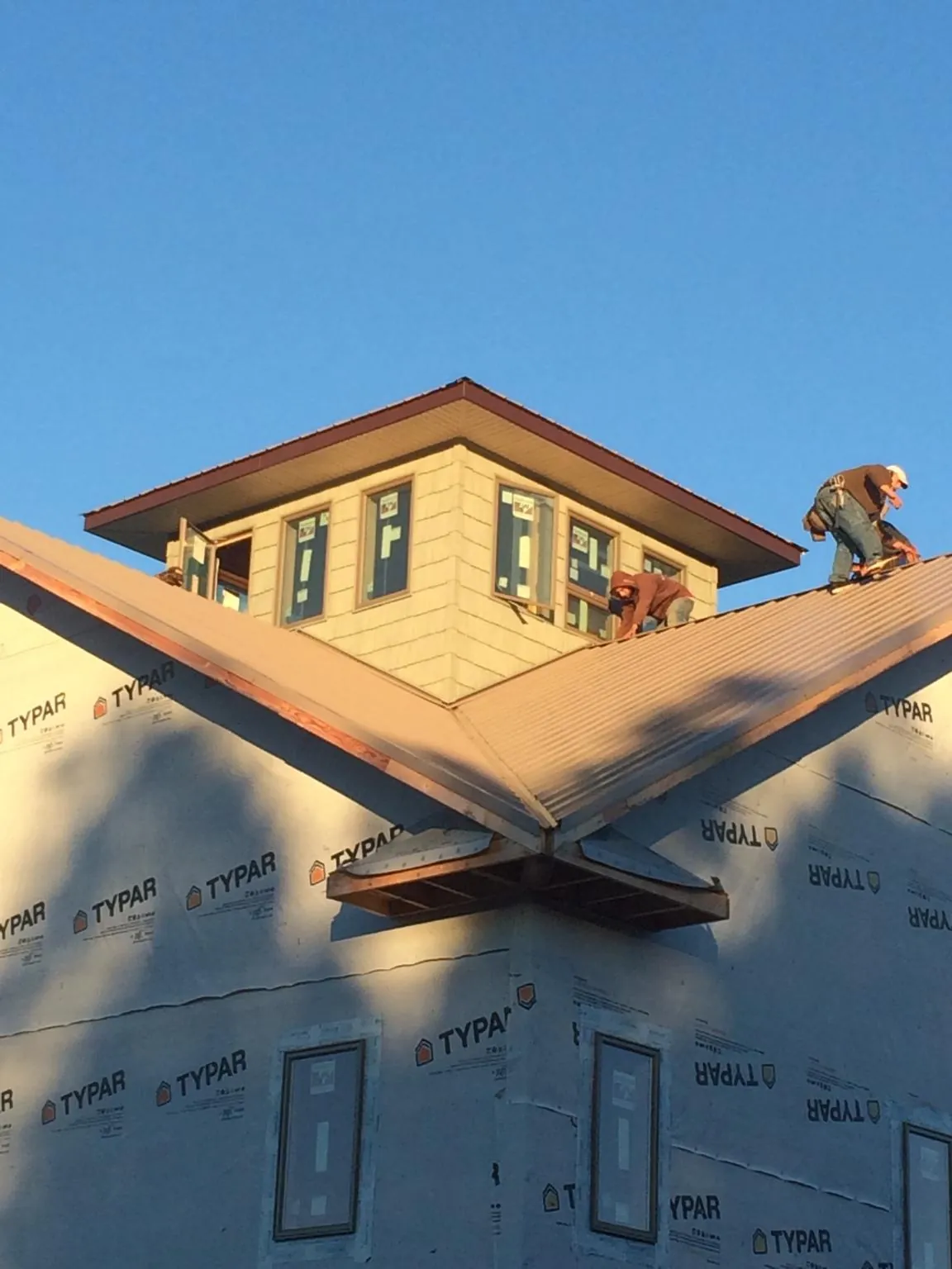 Roofers working around a rooftop cupola on a new metal roof at sunset — Roof Waterproofing in Horse Shoe by Roofing Brothers